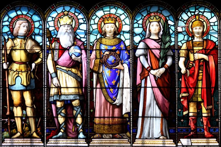 Vitraux représentant des saints catholiques dans une église, lumière colorée traversant les scènes sacrées.