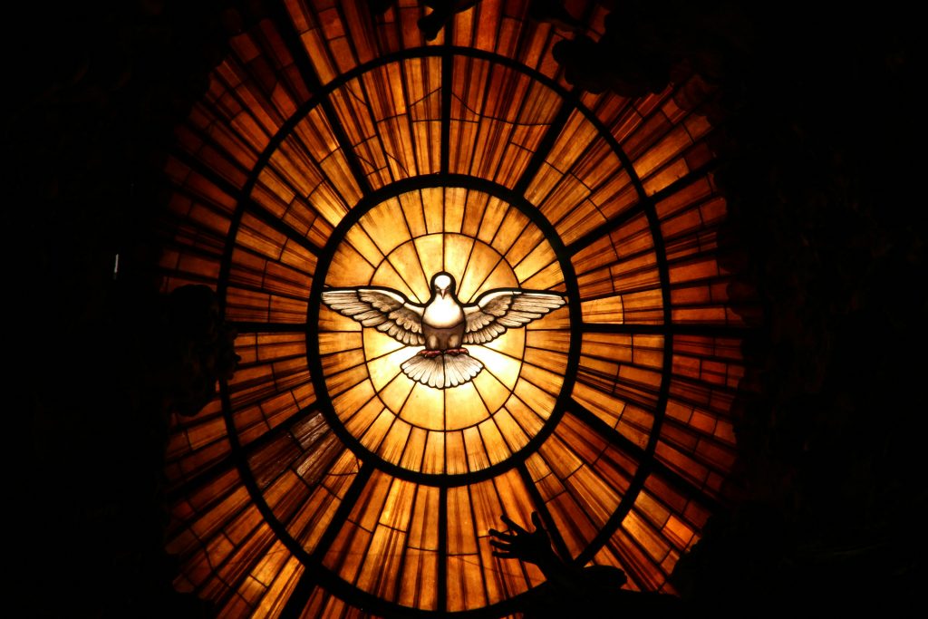 Colombe blanche descendante sur un vitrail aux couleurs sacrées, symbole de l'Esprit saint. Photo prise par Serge Taeymans.